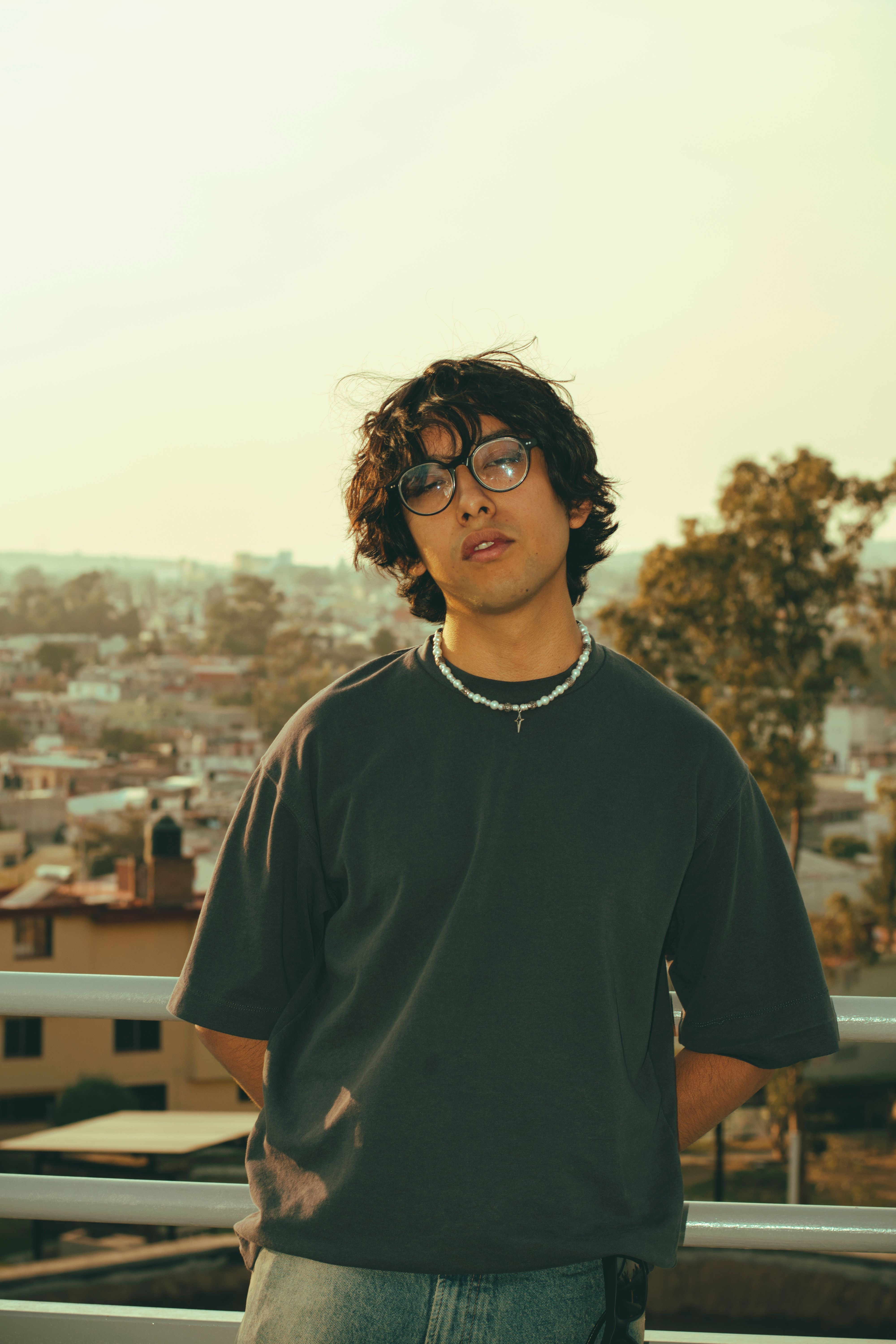 Casual portrait of a young man wearing glasses against a cityscape background.