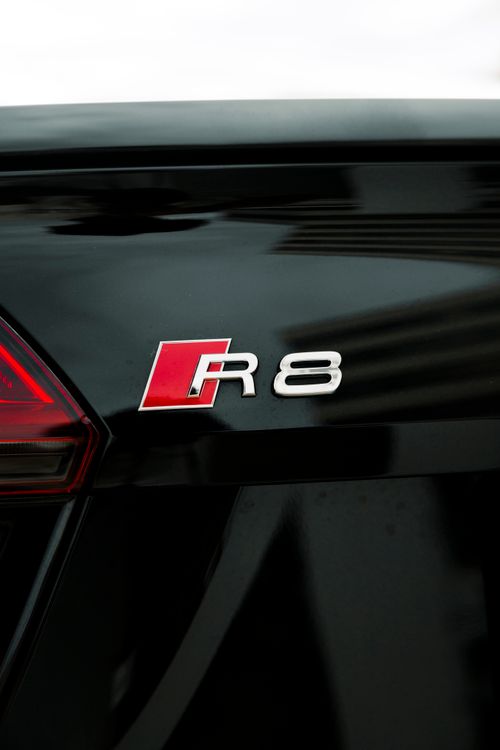 Free Detailed view of a luxury car emblem on a sleek black vehicle surface. Stock Photo