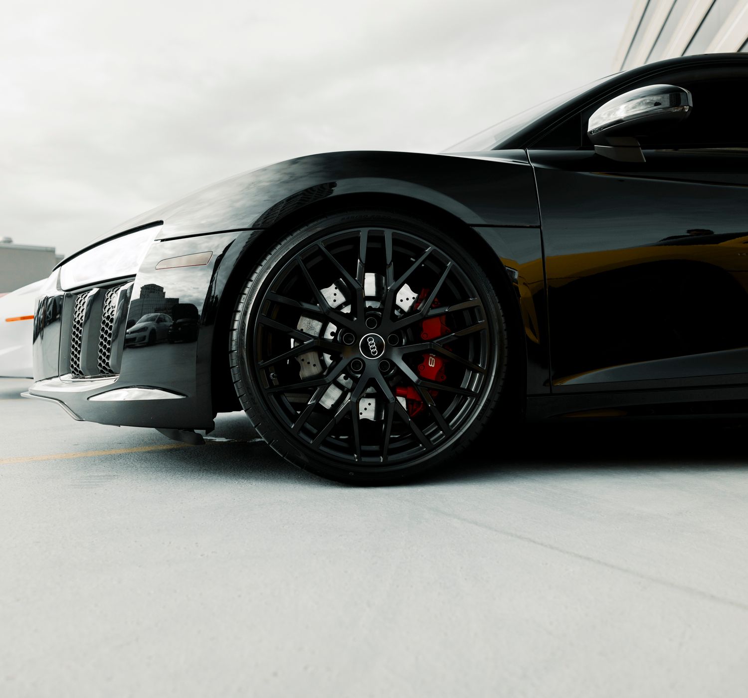 Close-up of a black luxury sports car's wheel detail in an outdoor setting.
