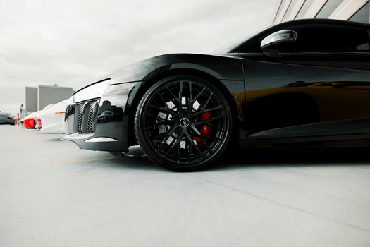 Close-up of a black luxury sports car's wheel detail in an outdoor setting.
