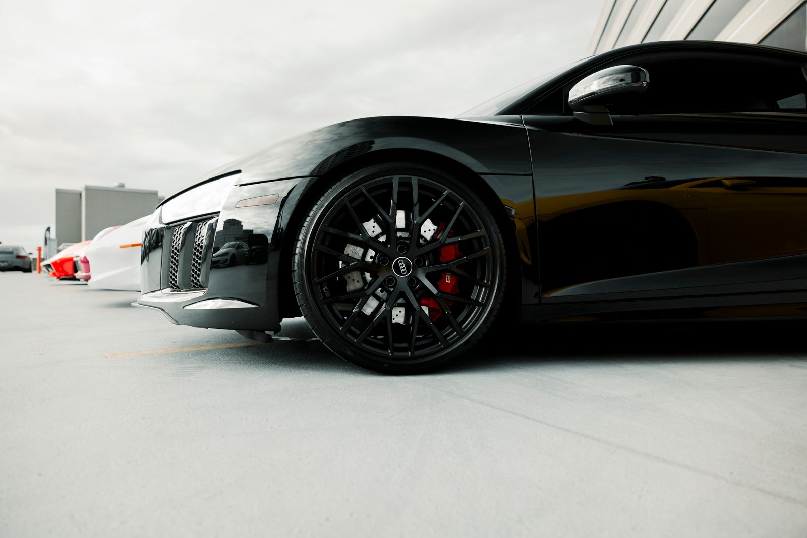 Finished black luxury coupe seen in three-quarter rear view with deep paint reflections and no installer present