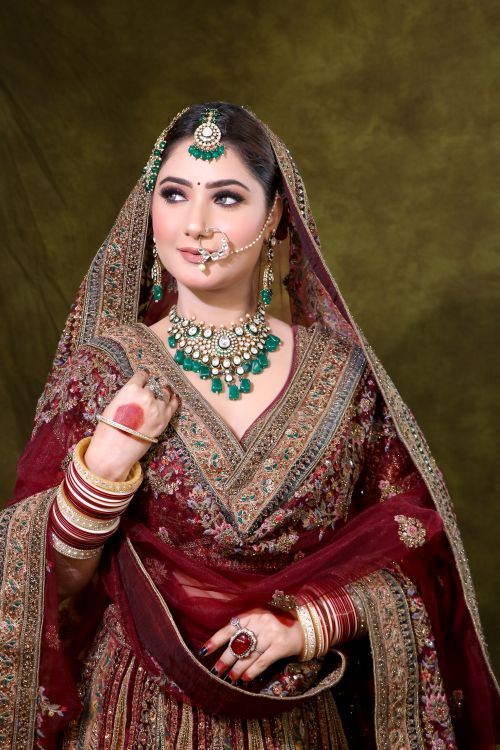 Free A beautiful bride in traditional Indian bridal attire with intricate jewelry and a rich maroon dress. Stock Photo