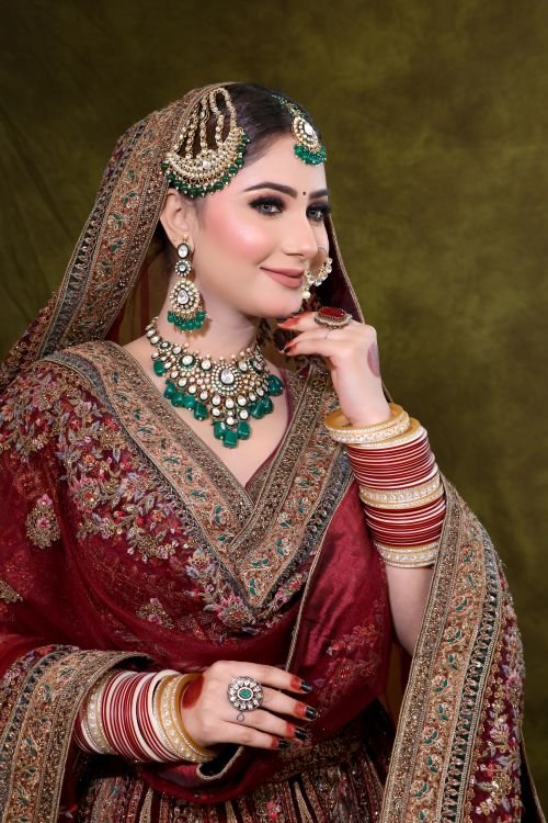 Free Beautiful bride in intricate maroon lehenga with stunning jewelry, posing gracefully. Stock Photo