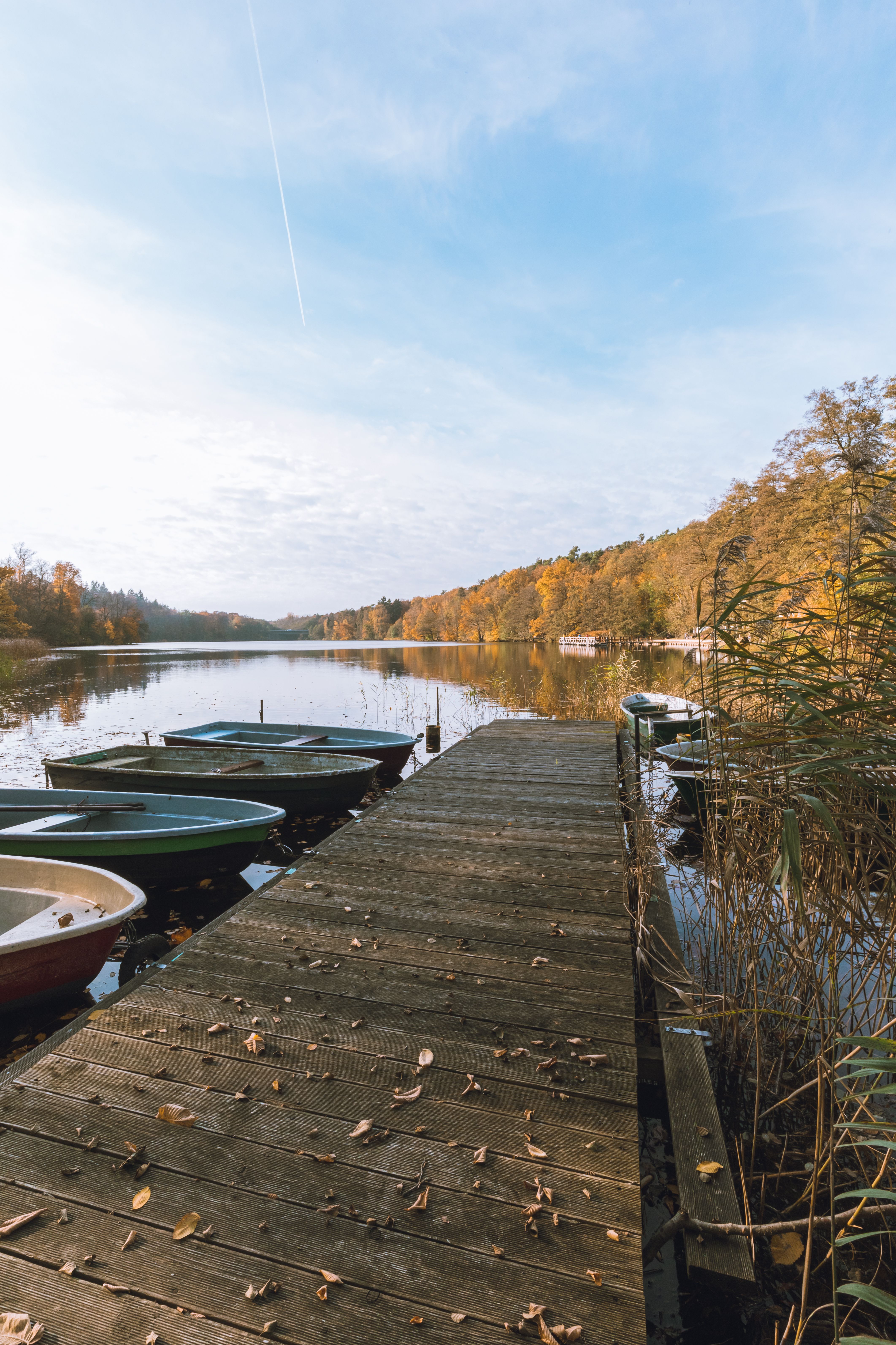 Serene Autumn Lake with Boats and Wooden Dock · Free Stock Photo