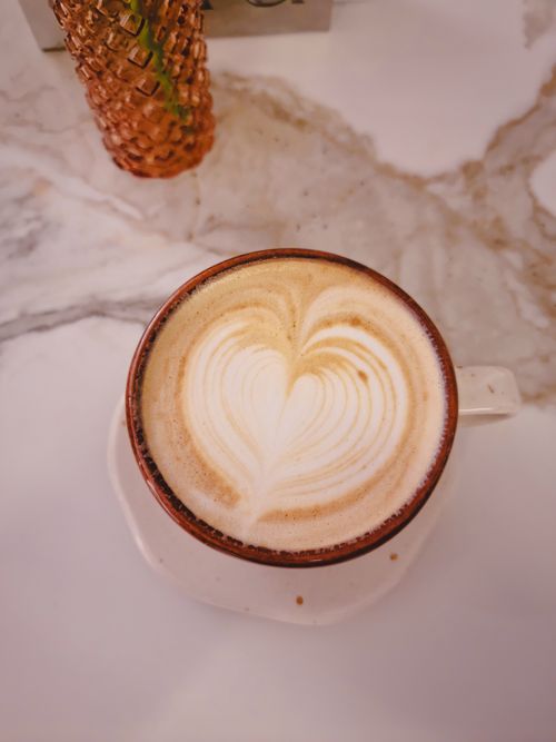 Free Explore the warm ambiance of a Bucaramanga café with a beautifully crafted latte. Stock Photo