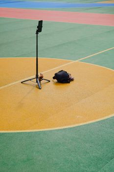 A vibrant basketball court with a phone on a tripod and a backpack.