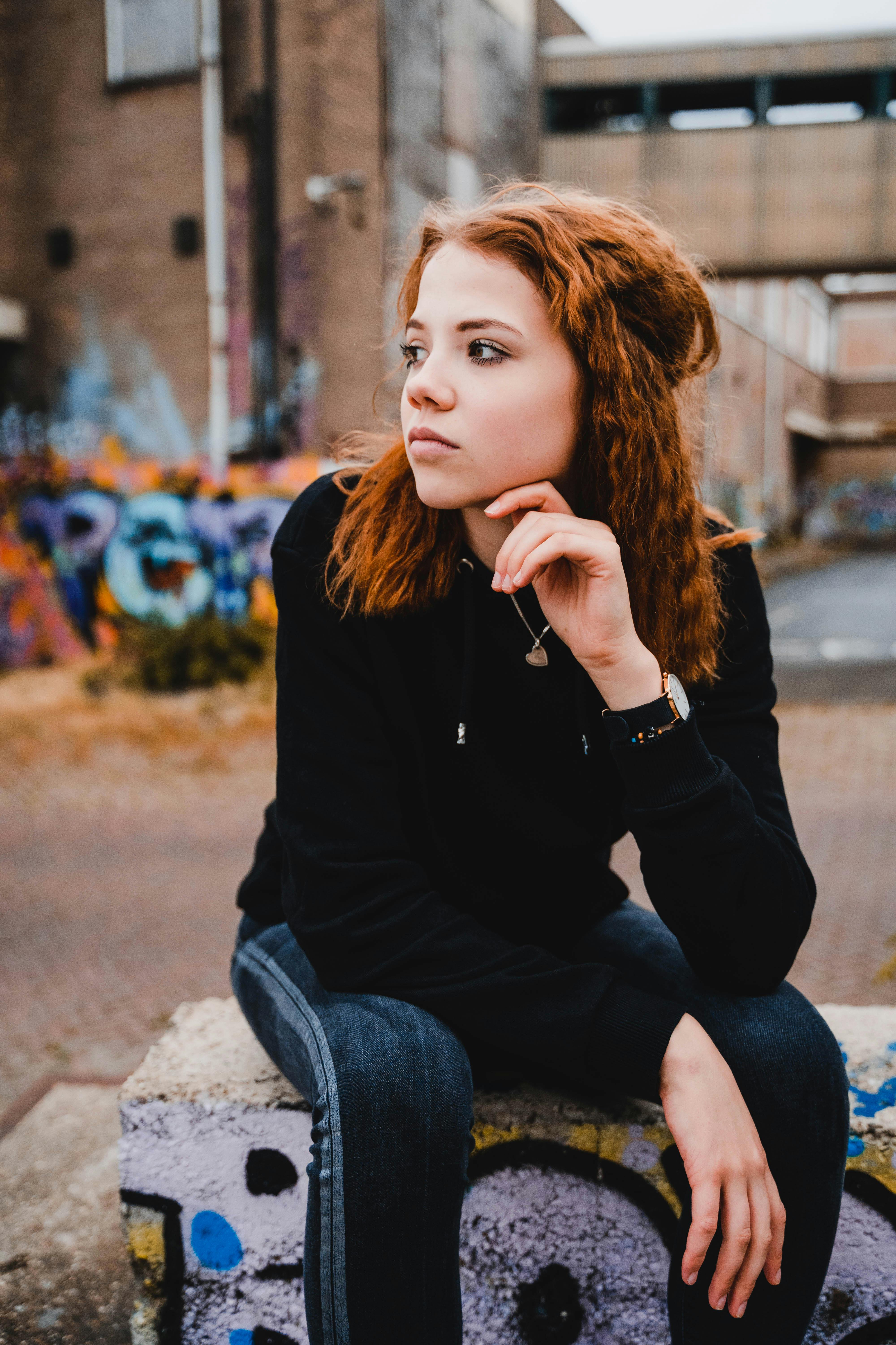 Woman in Black Sweater Sitting Outdoors · Free Stock Photo