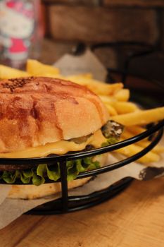 Cheeseburger with lettuce and cheese served with fries on a rustic surface.
