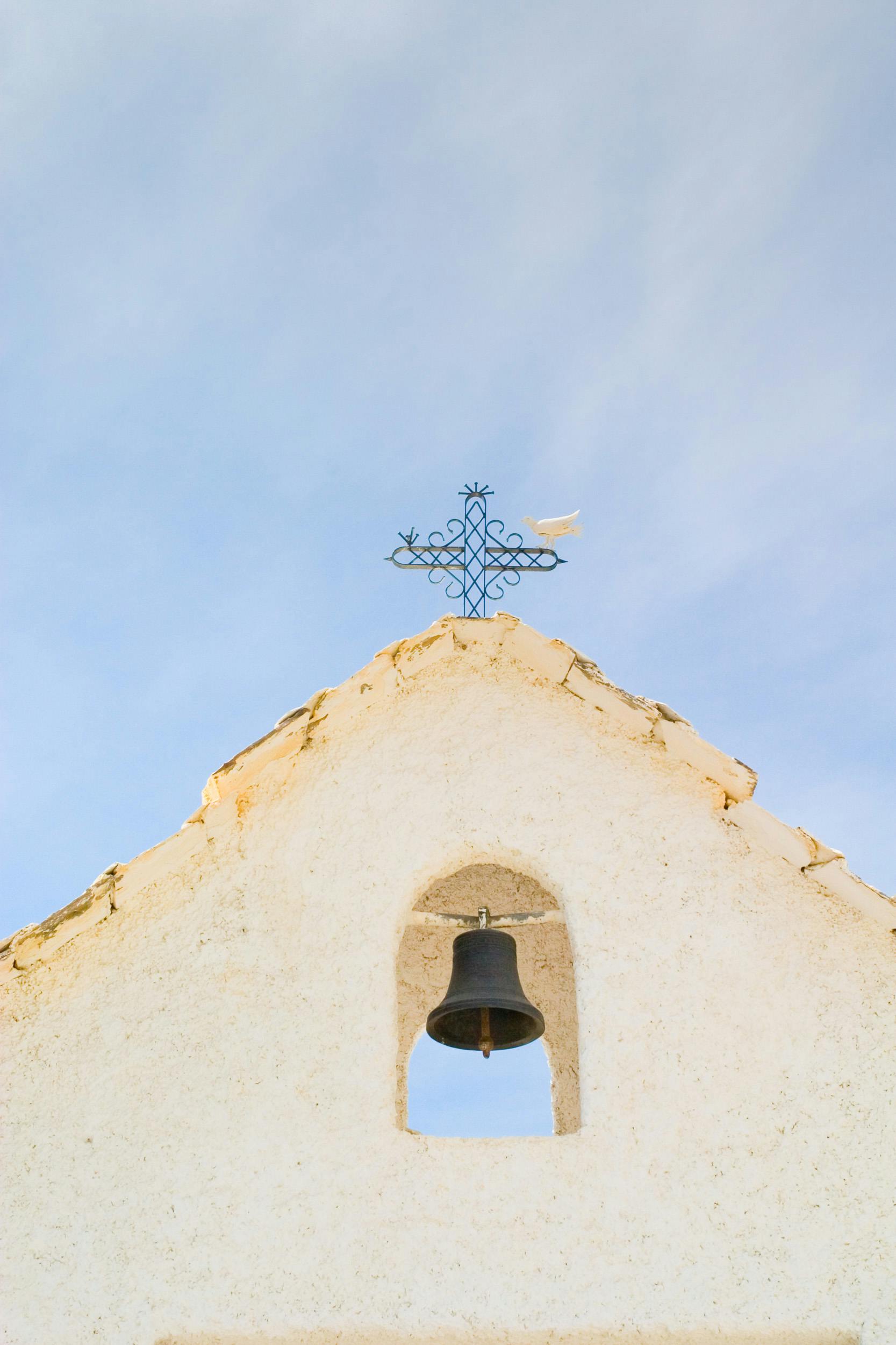 Scenic view of a traditional church bell tower with a blue sky backdrop in Ferreirola, Andalucía.
