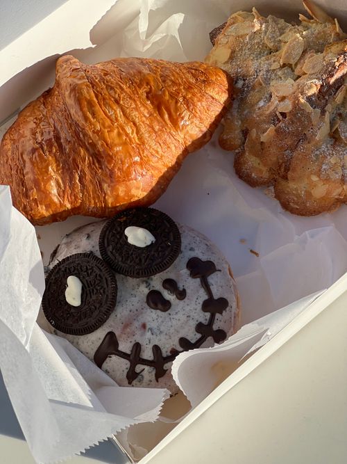 Free Delicious croissant, almond pastry, and Oreo-topped donut in a box. Stock Photo