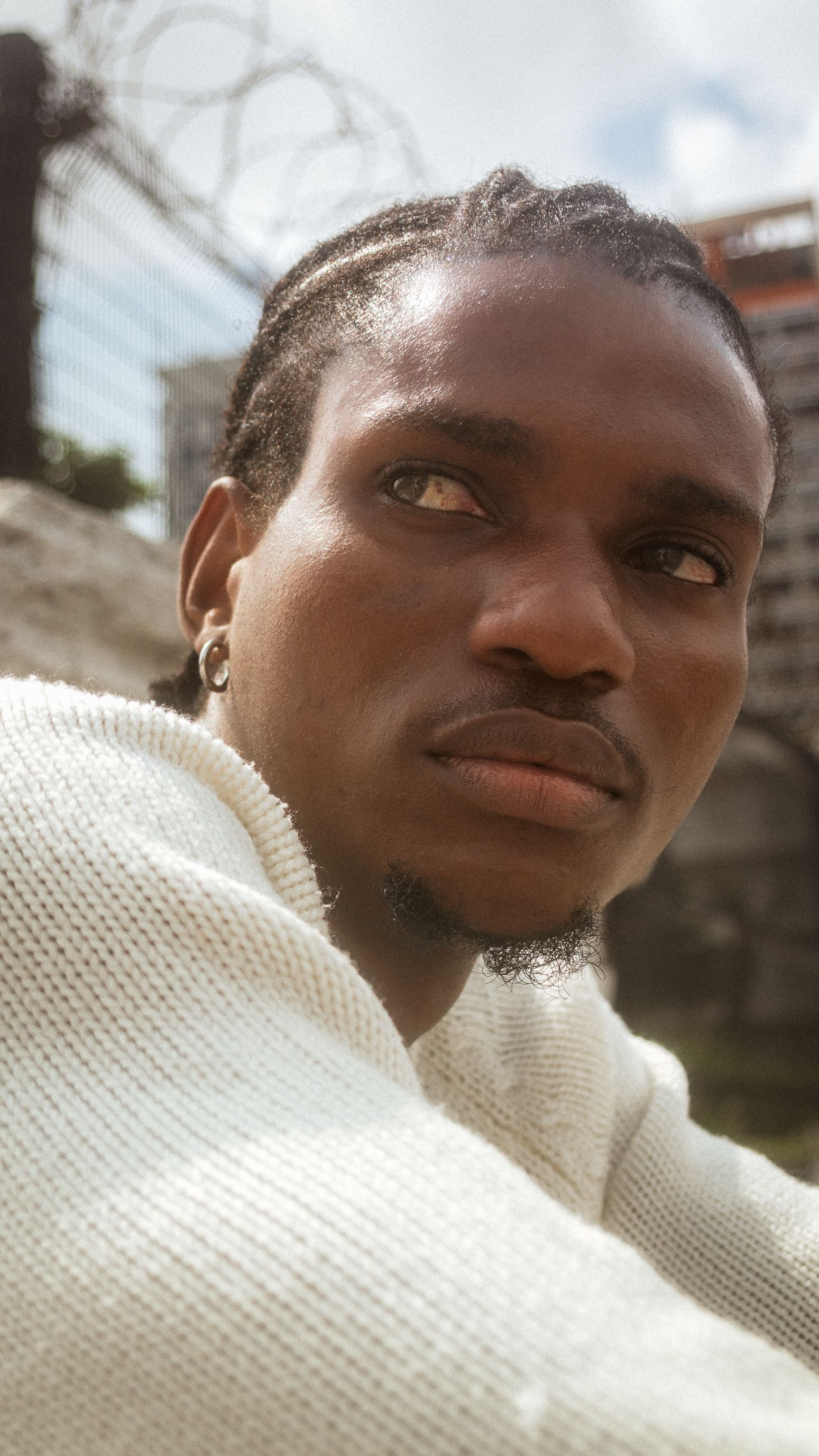 Portrait of a young man in a sunny urban environment, exuding thoughtfulness and style.