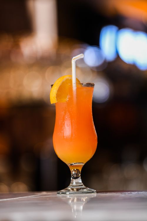 Free Vibrant orange cocktail with a slice and straw, perfect for a tropical getaway. Stock Photo