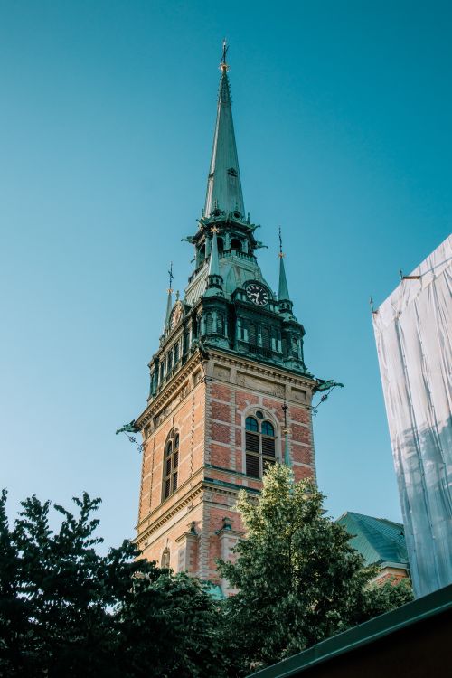 Free Gothic church tower with tall spire under a clear blue sky. Stock Photo