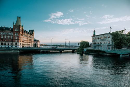 Free Elegant architectural scene of riverside cityscape at dusk with clear sky reflection in water. Stock Photo