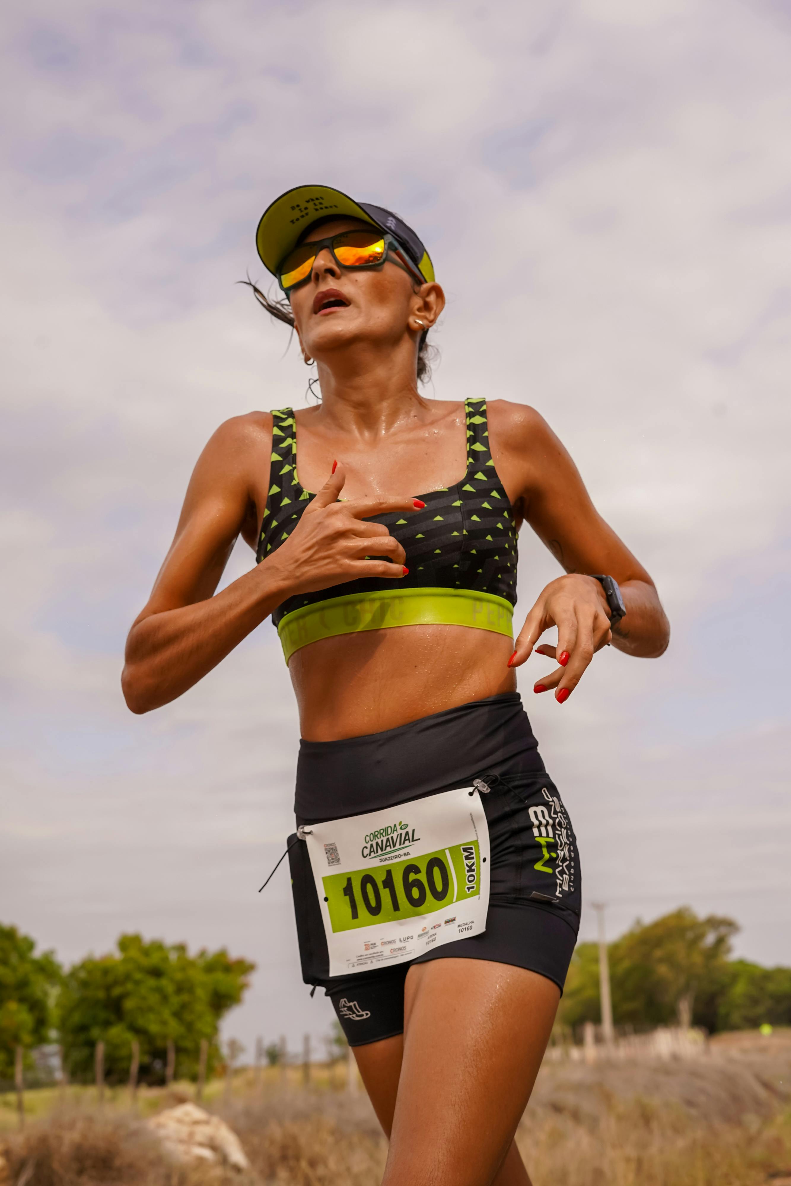 Focused female athlete running in an outdoor marathon wearing sportswear and a number bib.