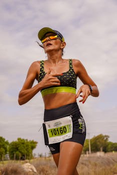 Focused female athlete running in an outdoor marathon wearing sportswear and a number bib.