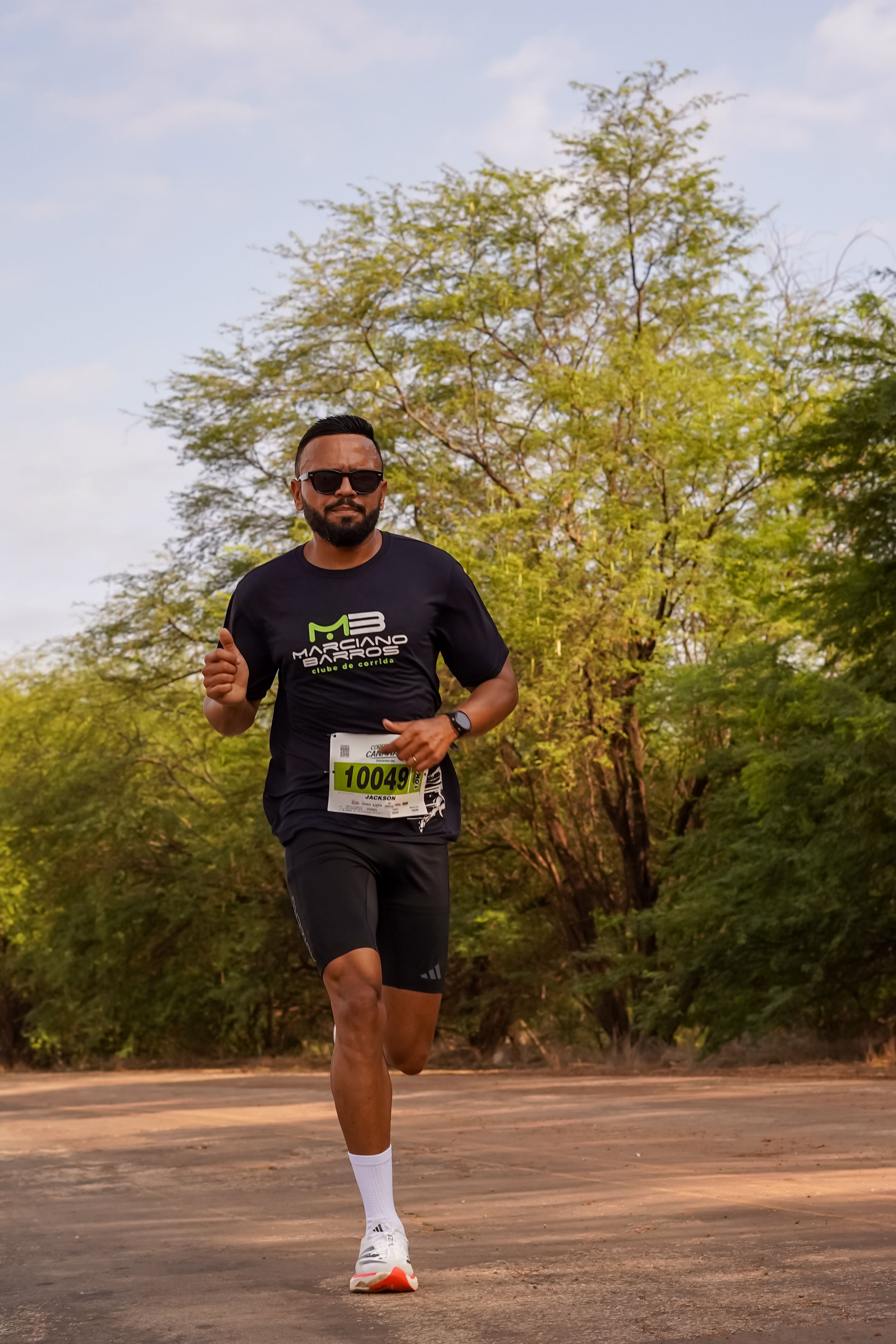 Athletic man running in a marathon race in a sunny outdoor setting.