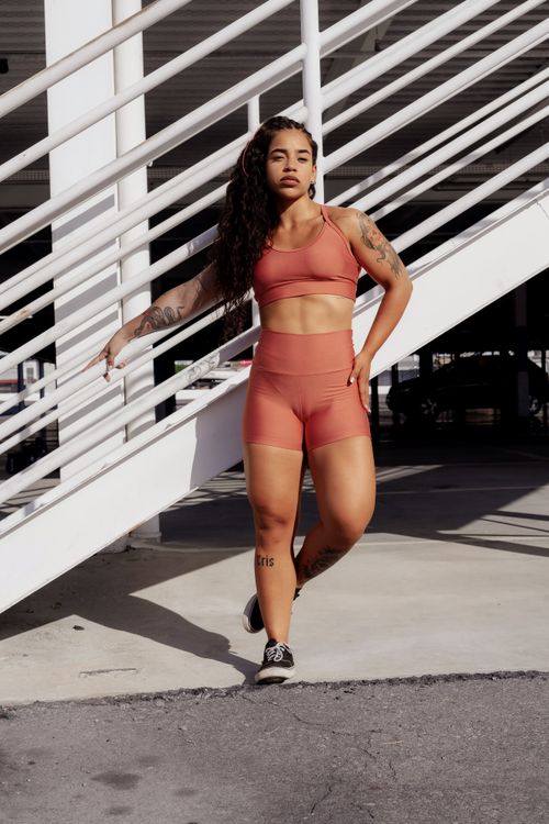 Free Fit woman wearing activewear, standing confidently outdoors by a staircase. Stock Photo