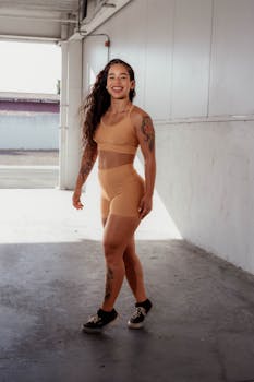 Smiling woman in workout attire posing confidently in an indoor setting.