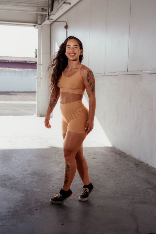 Free Smiling woman in workout attire posing confidently in an indoor setting. Stock Photo