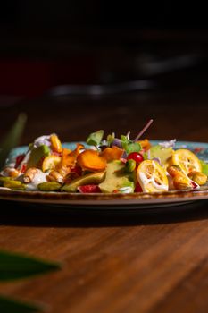 Vibrant gourmet vegetable salad featuring carrots, peppers, and dressing on a rustic wooden table.