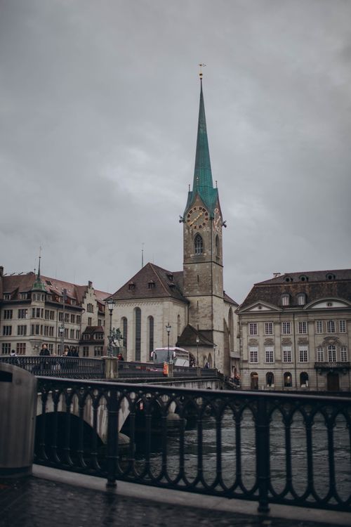 Free Gothic Fraumünster Church with its tower beside the Limmat River in Zurich, Switzerland, on a cloudy day. Stock Photo