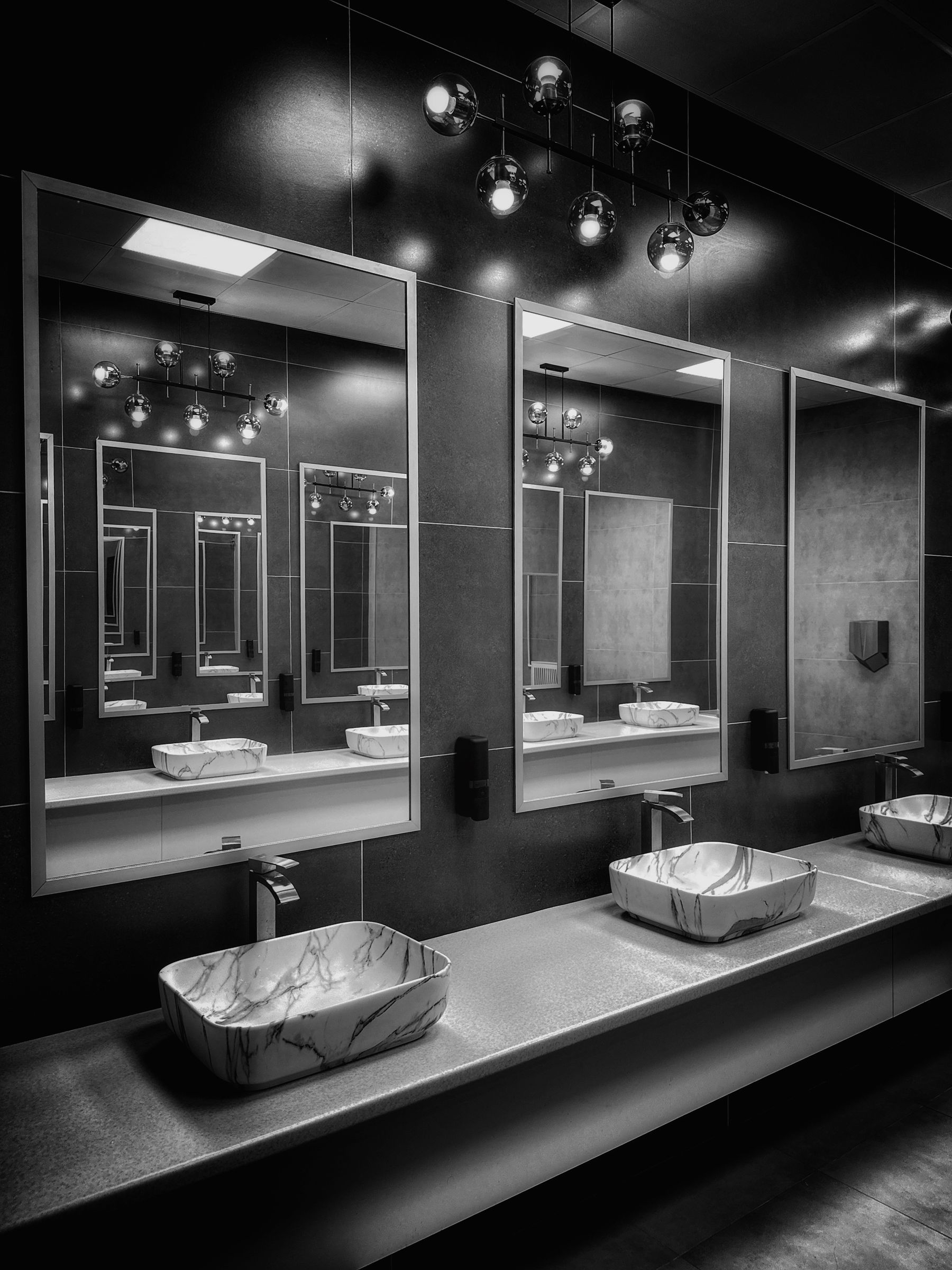 Black-and-white bathroom with repeated mirrors, symmetrical lighting and polished surfaces