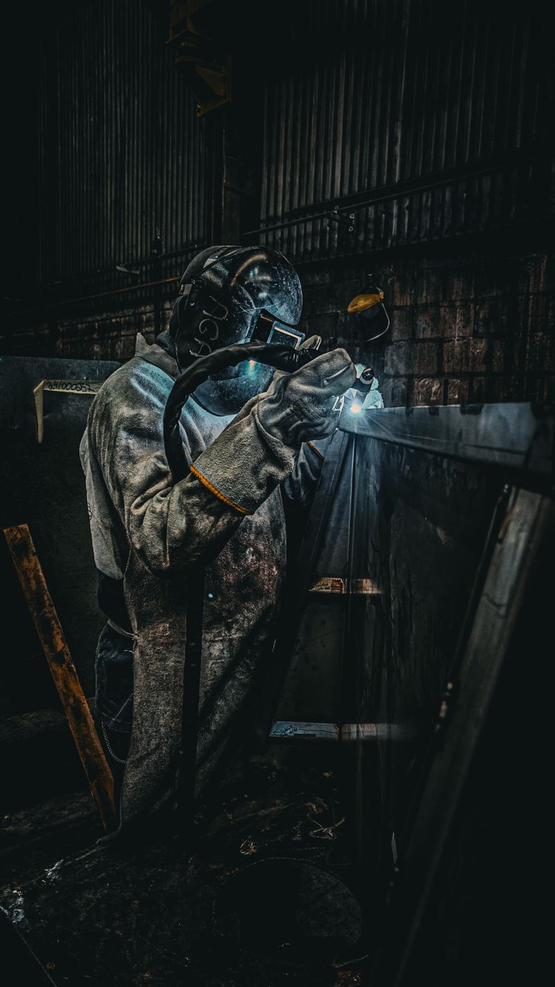 Industrial welding operation in factory with sparks and protective gear