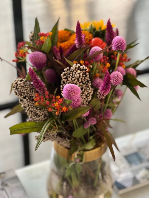 Free Bright wildflower bouquet with colorful blooms in a glass vase on a blurred background. Stock Photo