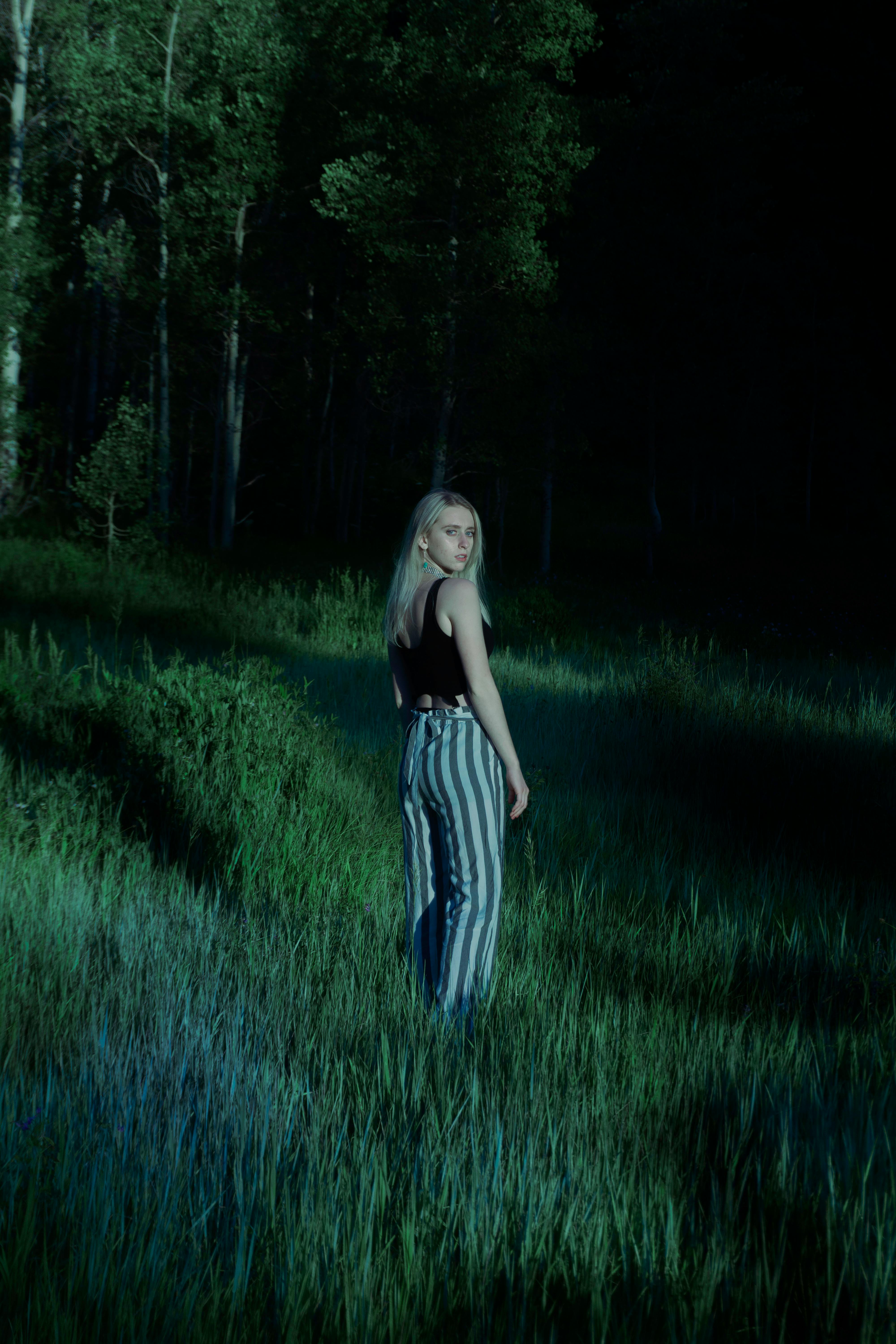 月光下的森林中，一位身着休闲装的金发女子摆着姿势，平添了几分神秘的光环