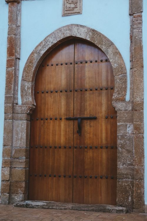 Free A beautifully crafted wooden door set within a stone arch, showcasing classic architectural design. Stock Photo