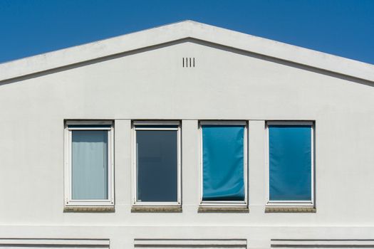 Symmetrical facade with three windows on a minimalist building under clear blue sky.