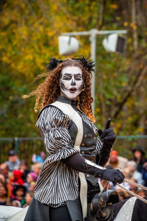Free A costumed performer with face paint and striped outfit participates in an outdoor autumn festival parade. Stock Photo