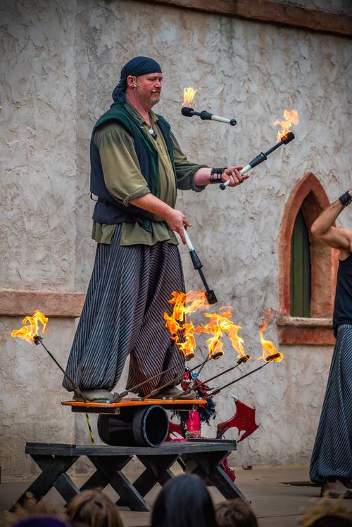 Free A performer skillfully juggles flaming clubs at a renaissance fair. Stock Photo