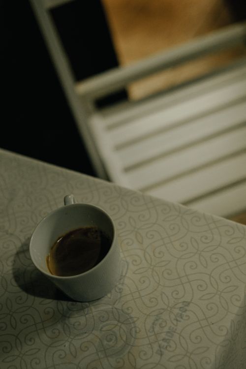 Free A moody scene with a coffee cup on a patterned table, evoking calmness. Stock Photo