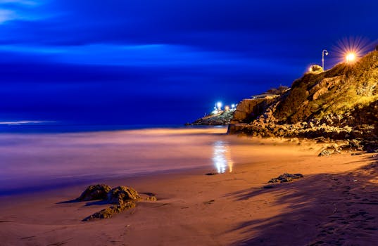 Quiet nighttime scene of Cullera beach with illuminated cliffs and serene sea.