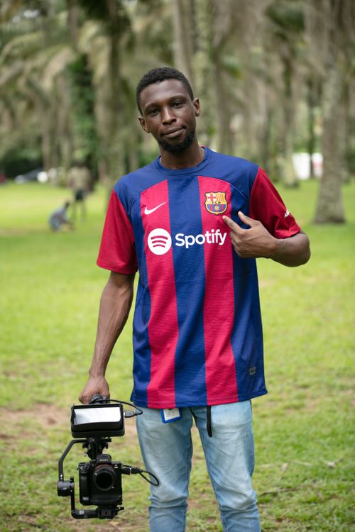 Free Portrait of a man holding a camera wearing a Barcelona jersey in a park setting. Stock Photo