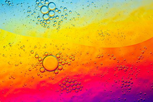 A vibrant abstract macro photo of oil bubbles on a gradient surface, creating a colorful pattern.