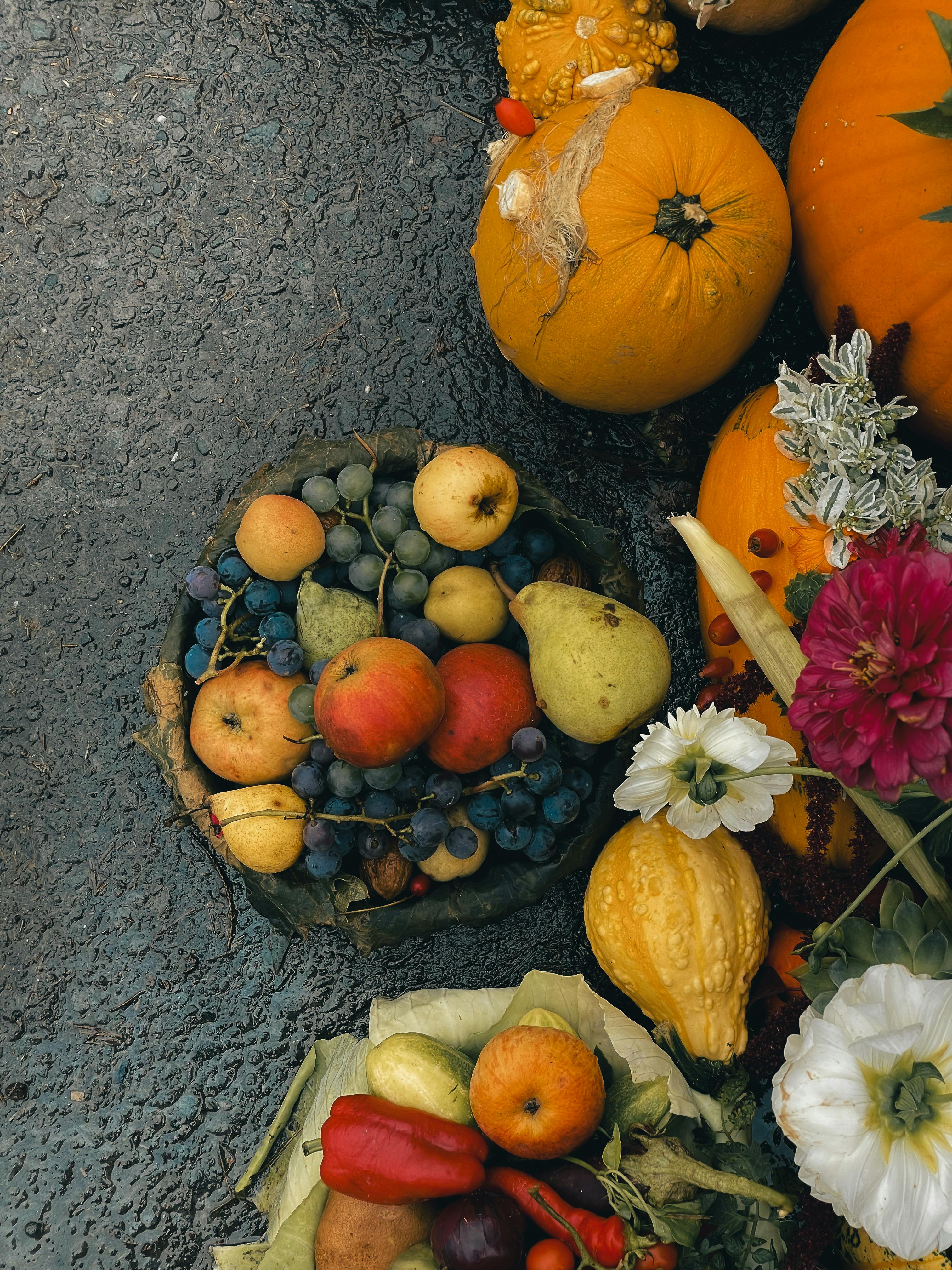 A vibrant collection of autumn fruits, pumpkins, and flowers on a textured surface. Perfect for fall themes.