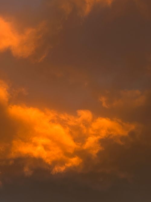 Free Capture of a vibrant orange sunset sky with dramatic cloud formations, creating a warm and vivid scene. Stock Photo