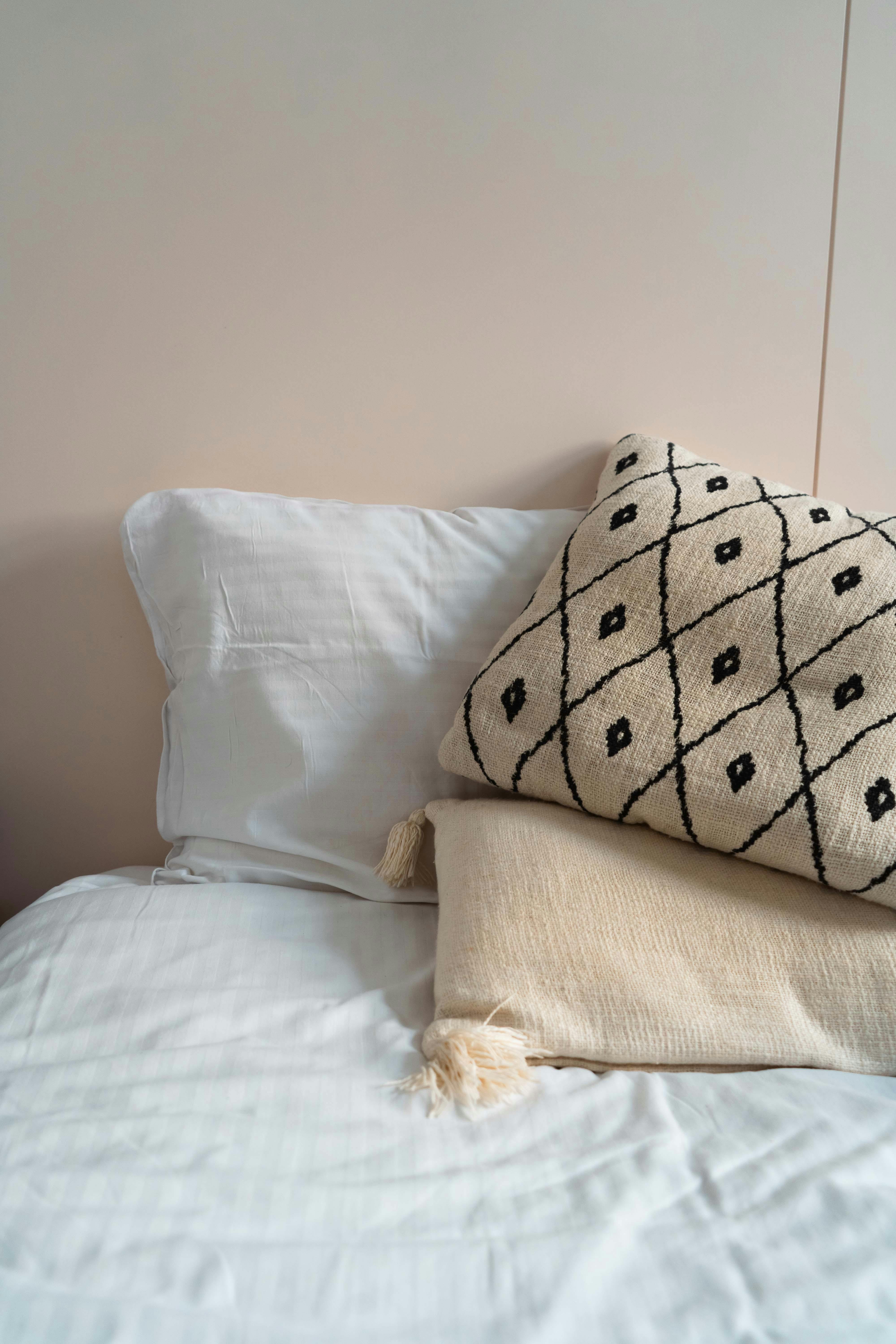 cozy white bed with patterned pillow