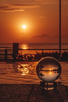 Crystal ball reflecting a vibrant São Paulo sunset over water.
