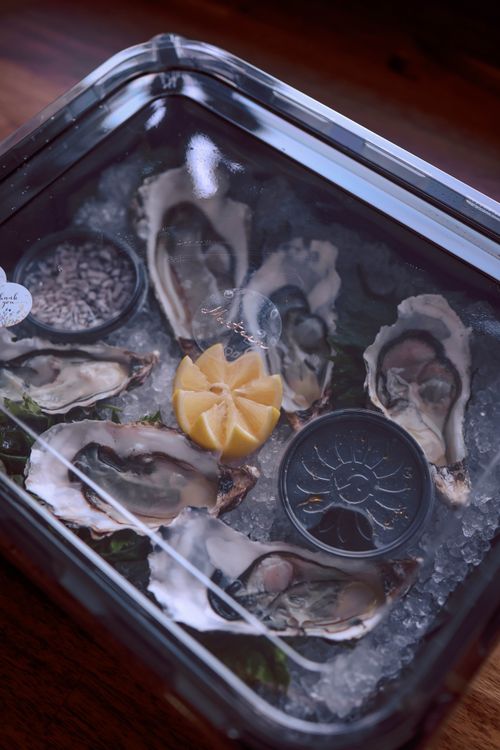 Free A seafood delicacy featuring fresh oysters on ice with a lemon slice, perfect for gourmet dining. Stock Photo