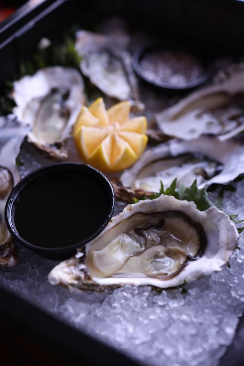 Free Close-up of fresh oysters on ice, served with lemon and sauce, perfect for seafood lovers. Stock Photo