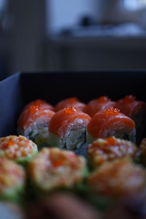 Free Deliciously arranged fresh salmon sushi rolls with avocado topping, ideal for food lovers. Stock Photo