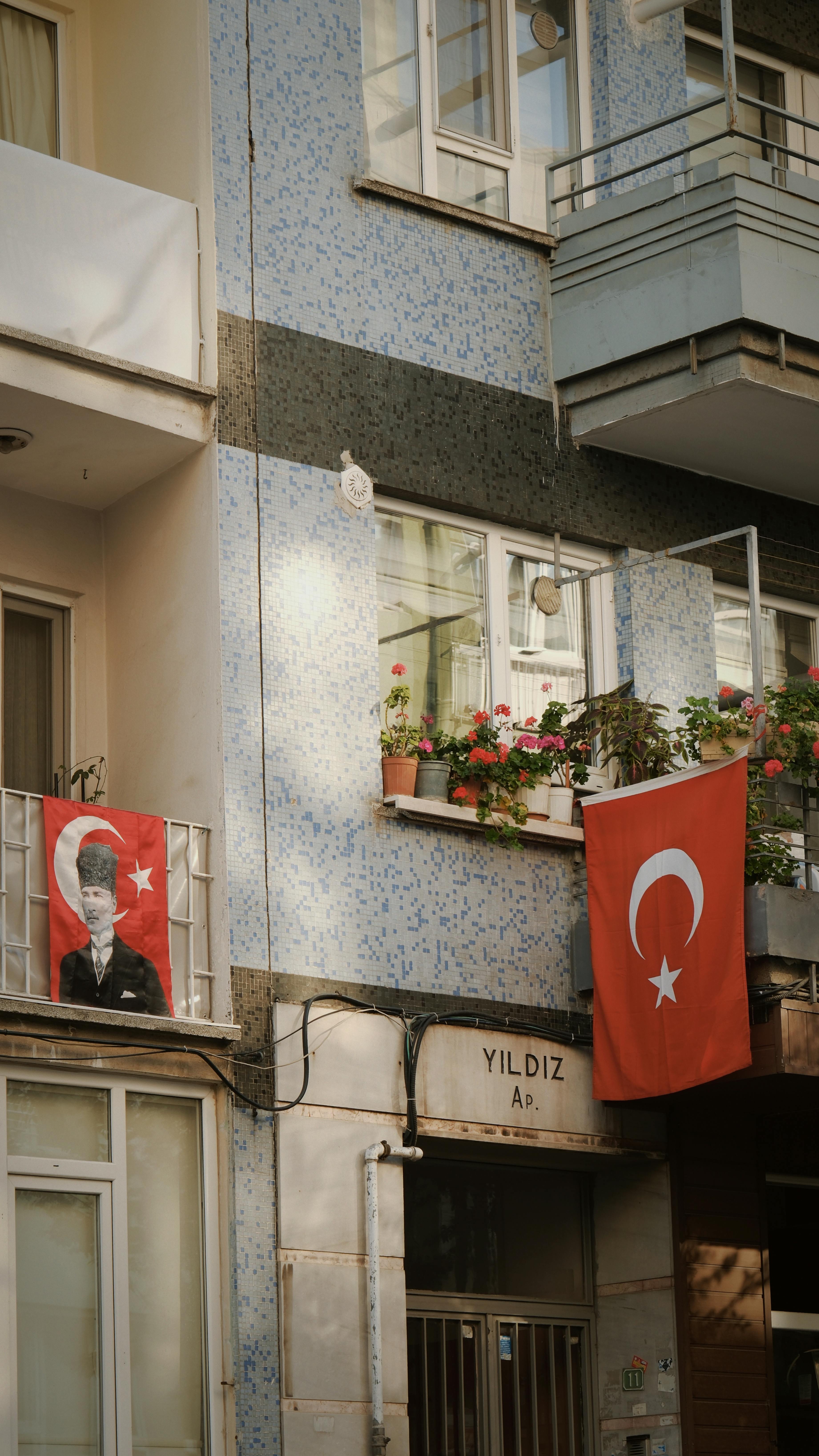 Turkish flags and Atatürk portrait on a residential building in Türkiye.