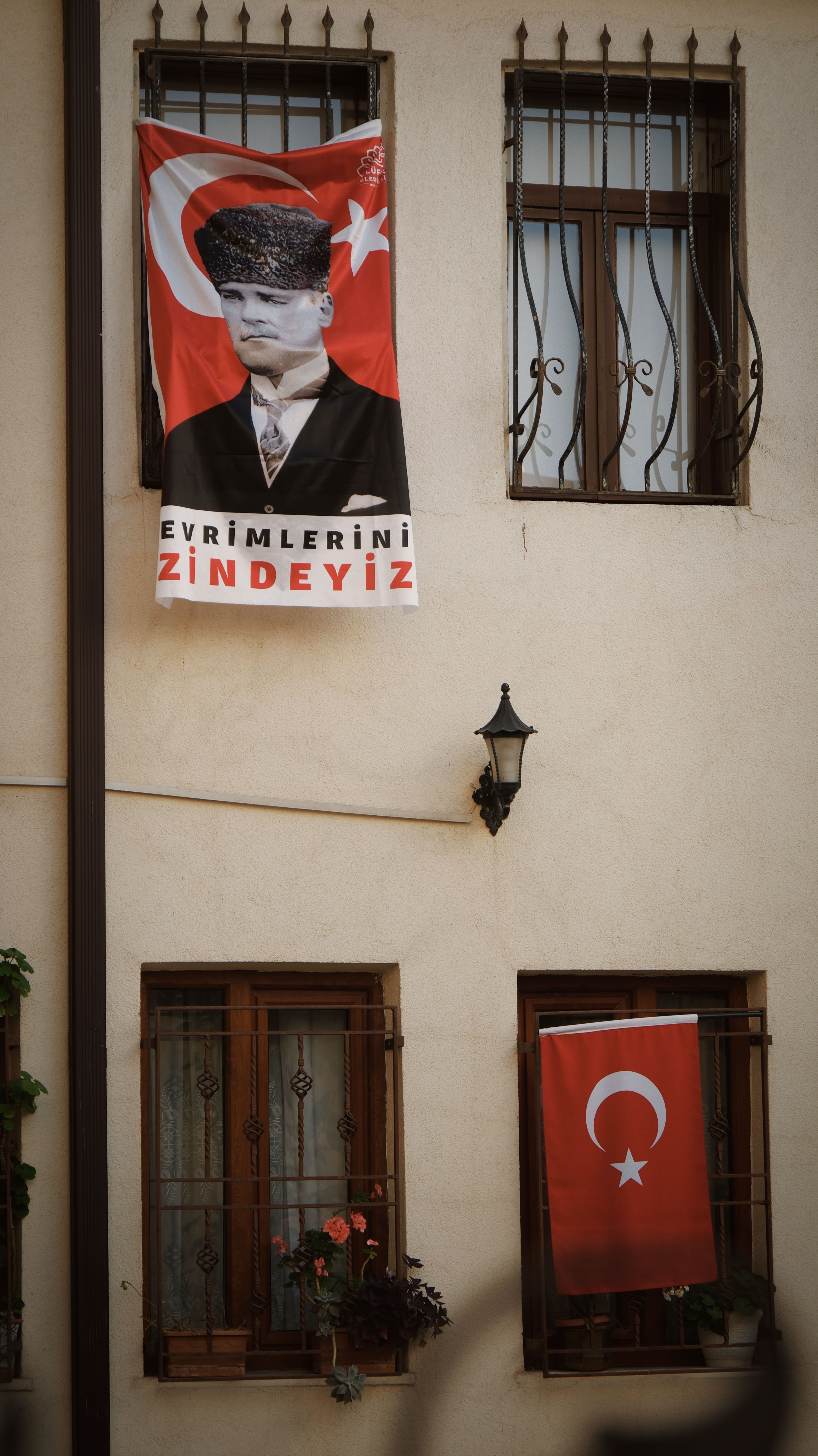 A Turkish building wall adorned with a portrait of Atatürk and national flags.