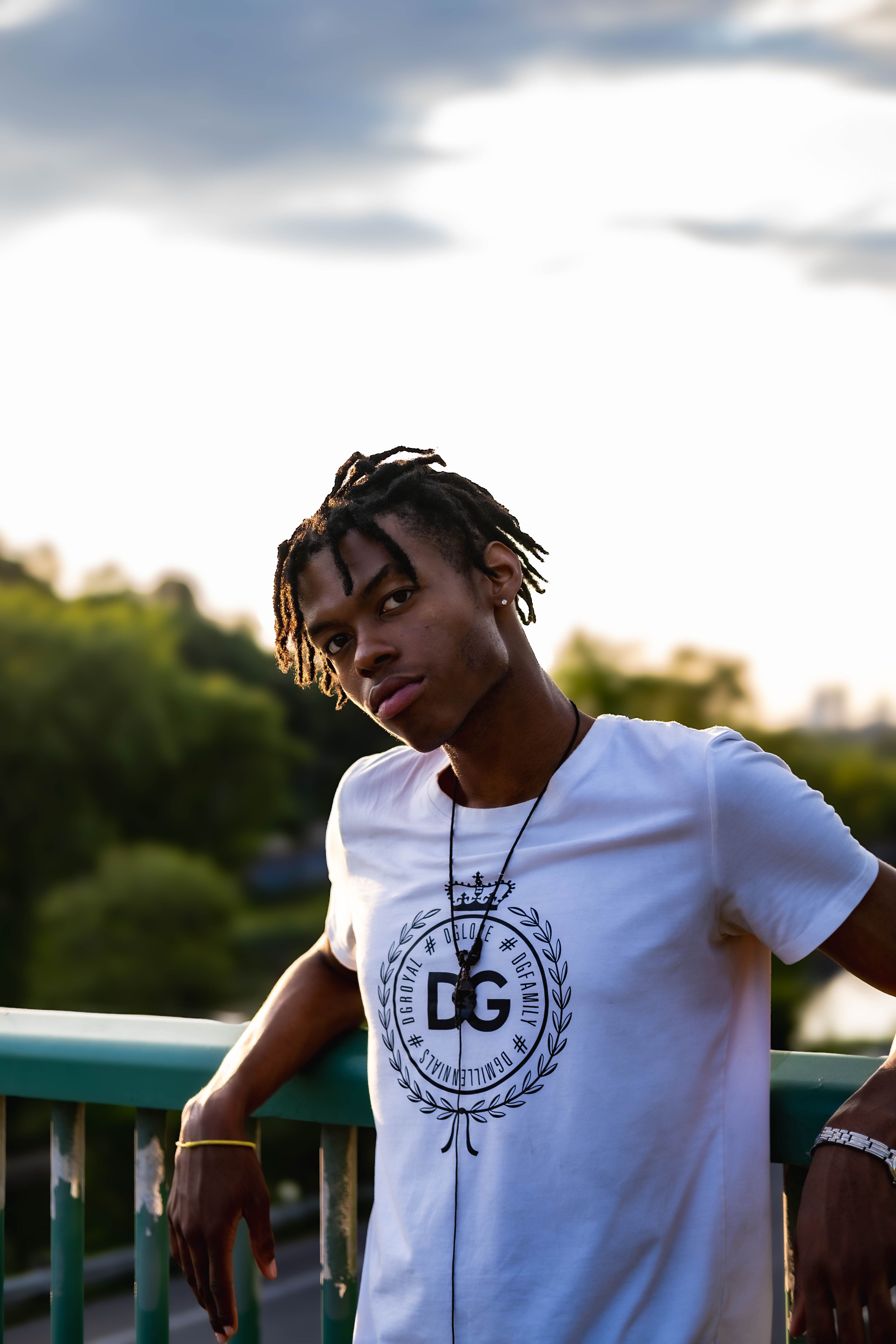 Portrait of a stylish young man leaning on a railing outdoors in Toronto, exuding confidence and artistry.