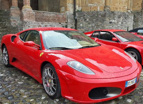 Free A vibrant red sports car parked outdoors on a historic cobblestone street, showcasing elegance. Stock Photo