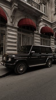 Stylish black SUV parked on a city street with elegant architecture and red awnings.
